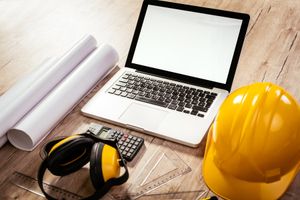 Architectural and engineering tools beside a laptop on a desk.