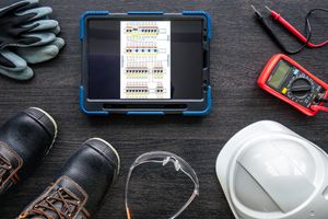 Electrical engineer workstation with safety gear and a tablet.