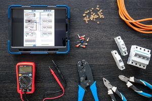 A technician reading an electrical wiring diagram on a tablet.