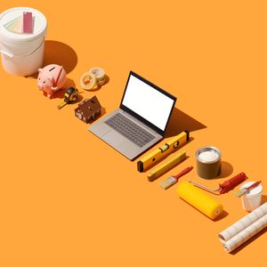 Renovation planning with a laptop, piggy bank, and supplies.