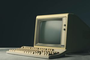 A retro computer display and keyboard on a desk.