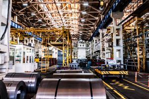 Rolls of iron plate on a modern factory floor.