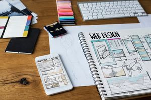 Web design sketches and digital mockups laid out on a desk.