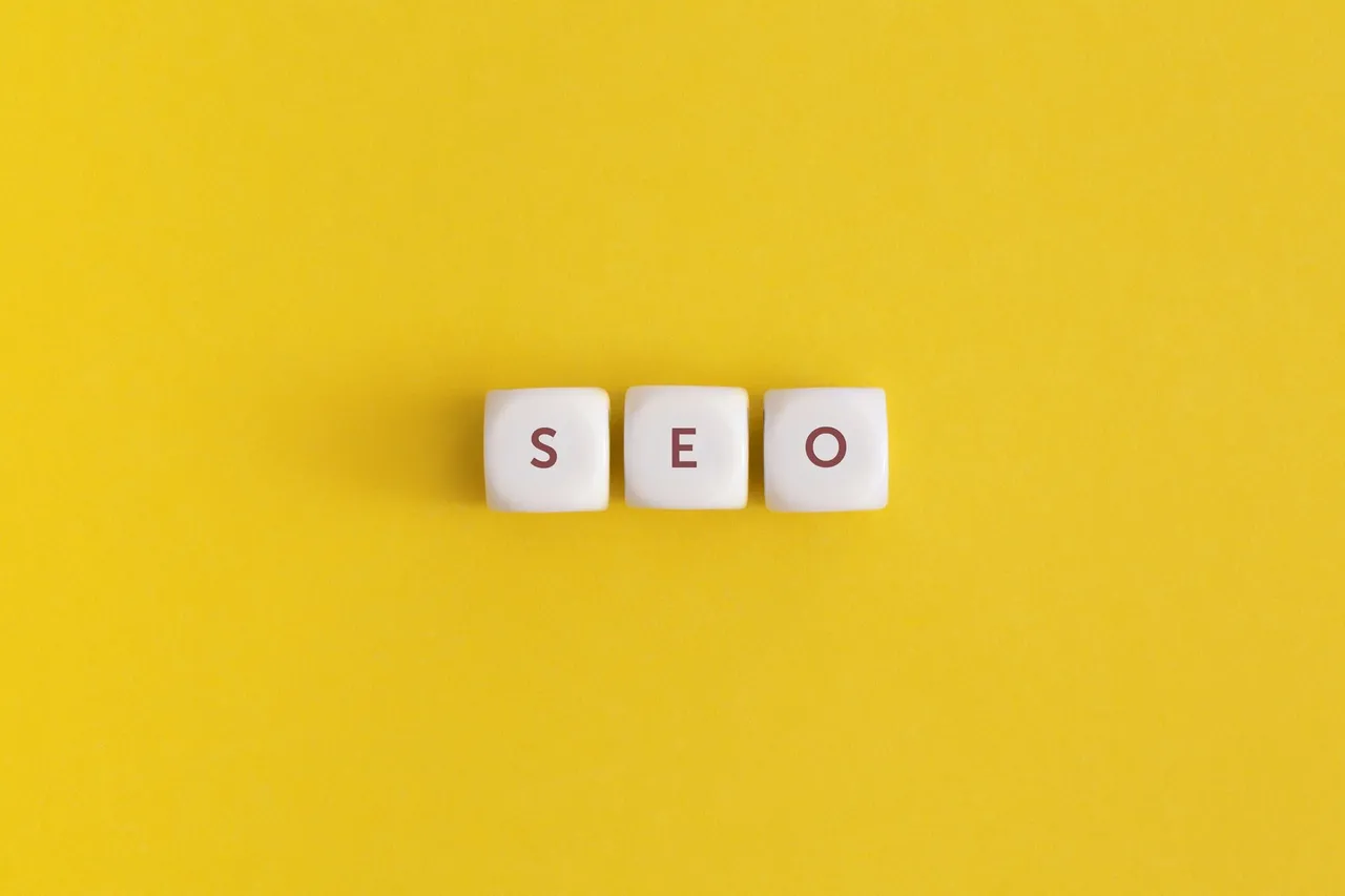 The word SEO on a yellow background, top-down flat lay.